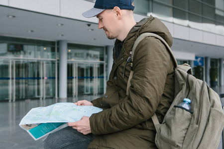 A tourist with a backpack is sitting and looking at the map for further journey.の写真素材
