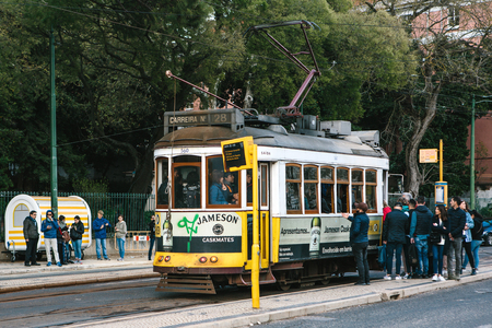 Lisbon, June 18, 2018: Locals try to get into the crowded old-fashioned yellow tram at the tram stop. The usual everyday city life.のeditorial素材