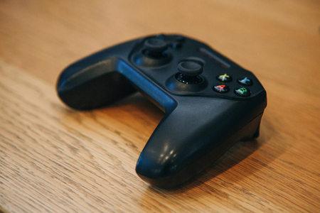 The game joystick from the company Apple lies on the wood background.のeditorial素材