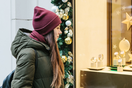 A young beautiful woman or girl looks at the shop window and chooses a Christmas gift.の写真素材