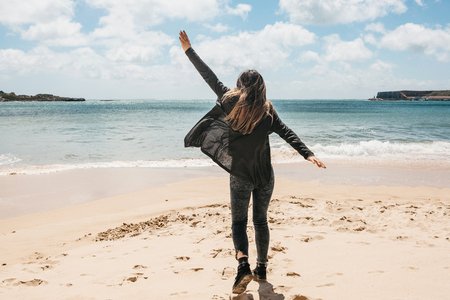 A young girl runs along the beach next to the Atlantic Ocean in Portugal and is happy.の写真素材
