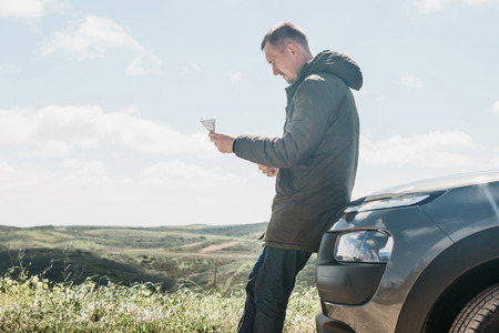 A tourist man next to the car looks at the map of the area for further travel.の写真素材