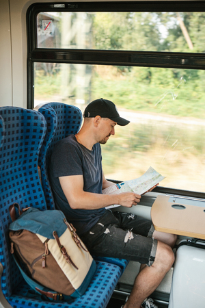 A tourist sits by the window in a train or commuter train and looks at a map.の写真素材