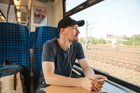 A young man listens to a music or podcast while traveling in a train.の写真素材
