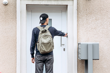 The tourist rings the doorbell to check in to the room he has booked or the student with the backpack returns home after classes at the institute or on vacation.の写真素材