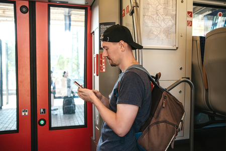 A tourist on the train uses a mobile phone to call or send a message or view a map or mobile application.の写真素材