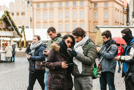 Prague, December 25, 2017: A young couple of tourists looks at a map on a cell phone on the main square in Prague during the Christmas holidays.のeditorial素材