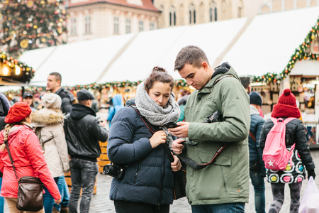 Prague, December 25, 2017: A young couple of tourists looks at a map on a cell phone on the main square in Prague during the Christmas holidays.のeditorial素材