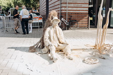 Germany, Muenster, October 5, 2018: A street artist performs living statue covered with dried mud, as if it were in a desert.のeditorial素材