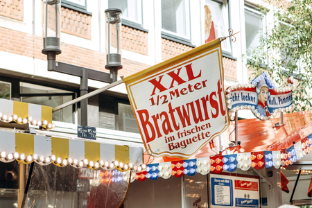 Germany, Muenster, October 5 2018: Street tent selling fried sausage. The inscription in German translates fried sausage in a fresh baguette. Advertising on top of the tent. Small business at the city fair.のeditorial素材