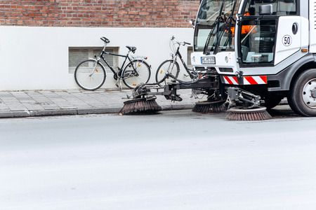 Germany, Muenster, October 5, 2018: A special truck or street cleaning vehicle rides along the road and cleans the street from dirt and dust.のeditorial素材