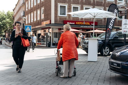 Germany, Muenster, October 5, 2018: An elderly woman with a special cart for the elderly is walking down the street.のeditorial素材