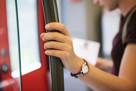 A tourist girl or a student inside the subway or train looks at a map and waits for its stop to go outside. Selective focus on the hand. Travel concept.の写真素材