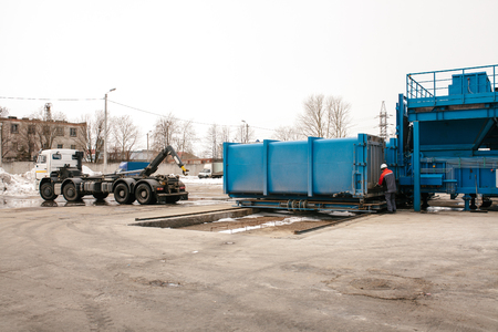 A special heavy machine loads a container with sorted waste at the plant for sorting waste to be transported to another plant for recycling.の写真素材
