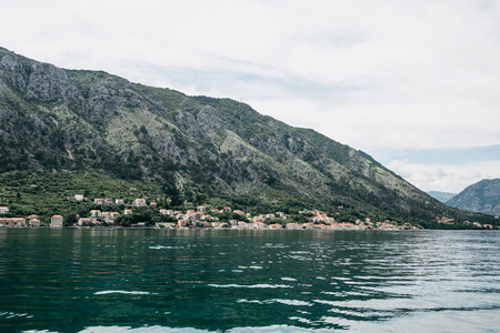 Beautiful view from the sea on the coastal town near the mountain in Montenegro.