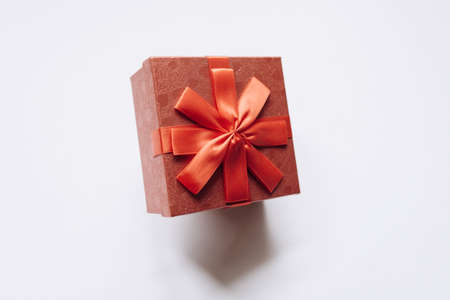 Red box with a bow with a gift on a white background.