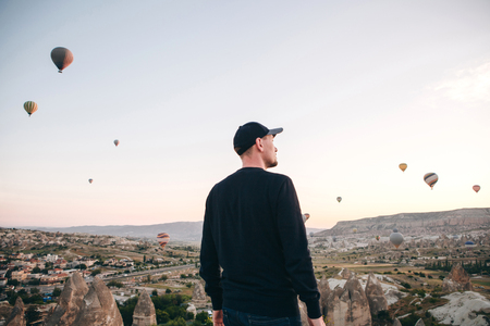 A man in solitude admires a beautiful view of the flying balloons in Cappadocia in Turkey.の写真素材