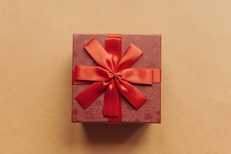 Red box with a bow with a gift on a yellow background.の写真素材
