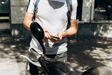 A guy or a tourist activates or rents an electric scooter using a mobile application on a cell phone to travel around the city. Electric scooter is a popular vehicle in Berlin in Germany.の写真素材