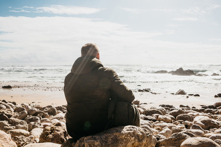 A man with a backpack or a tourist or a traveler in solitude admires a beautiful view of the Atlantic Ocean in Portugal. Search for soul or unity with nature.の写真素材