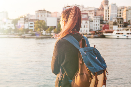 Young tourist girl with a backpack at sunset next to the Bosphorus on the background of Istanbul.の写真素材