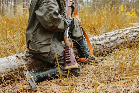 Hunting. Woman hunter holding a gun in the autumn forest