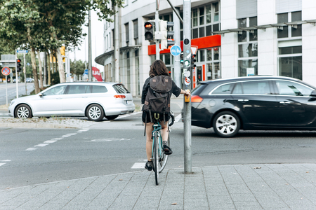 The girl on the bike stopped at a red light and waiting for when to go. Riding a bike or a healthy lifestyle.の写真素材