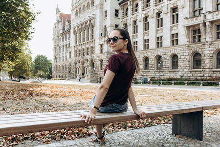A young beautiful girl is sitting on a bench on the street in Leipzig in Germany and is resting.の写真素材