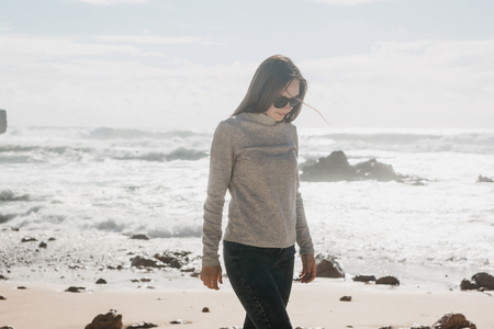 A young beautiful girl walks along the coast in solitude and thinks or is engaged in looking for the soul.の写真素材