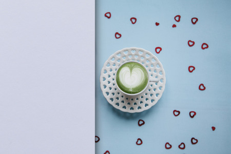 A cup with a tasty and aromatic morning matcha latte coffee on a festive background with many...