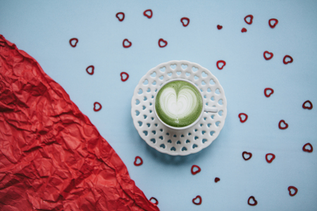 Fresh green Matcha coffee with a heart pattern on a festive background with many hearts. Concept for Valentine's Day or Women's Day.の写真素材