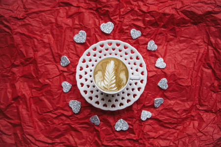 Fresh cappuccino coffee on a festive background with many hearts. Concept for Valentine's Day or Women's Day.の写真素材