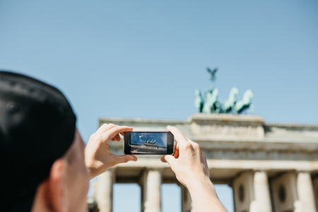 Tourist photographs on a mobile phone the Brandenburg Gate in Berlin in Germany. Sightseeing.の写真素材
