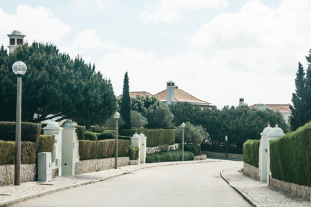 View of an asphalt road along a traditional street full of plants and houses in southern Portugal. Residential area in the suburbs.の写真素材