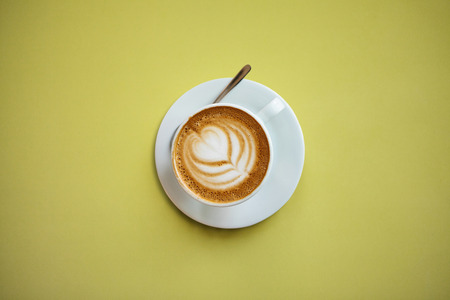 A cup with a traditional tasty and aromatic morning cappuccino on a yellow background.の写真素材