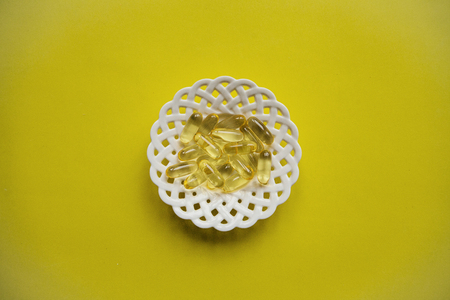 Many transparent pills Omega 3 or fish oil on a yellow background.の写真素材