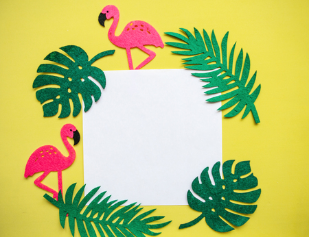 Summer design. Flamingos with tropical leaves on a yellow background. In the middle is a space for text.の写真素材