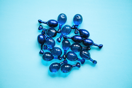 Fillers or capsules with hyaluronic acid on a blue background. Skin care and facial health.の写真素材