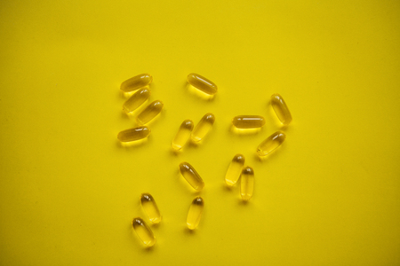 Many transparent pills Omega 3 or fish oil on a yellow background.の写真素材