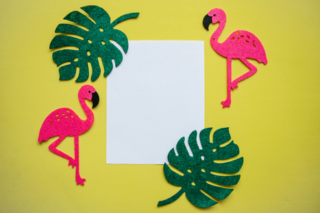 Summer design. Flamingos with tropical leaves on a yellow background. In the middle is a space for text.の写真素材