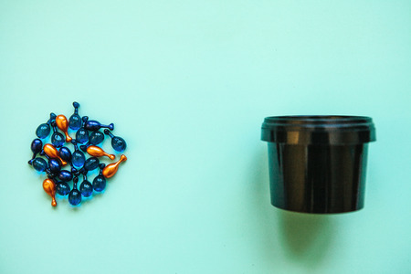 Many pills or capsules with hyaluronic acid and q10 or coenzyme next to a can or container with a face cream. Caring for skin health.の写真素材