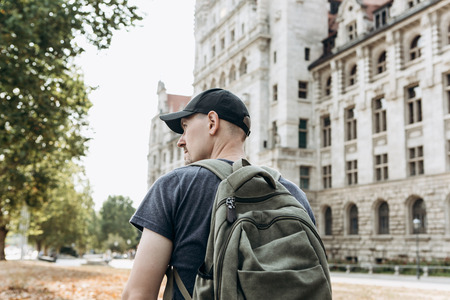 A young man or tourist or student with a backpack looks at the sights in Leipzig in Germany.の写真素材