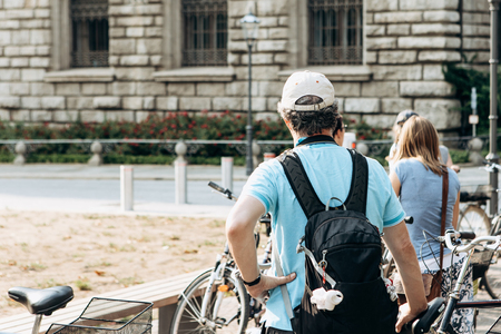Tourists on the bikes sightseeing. Excursion on bicycles. Rear view of an unrecognizable man with a backpack.の写真素材