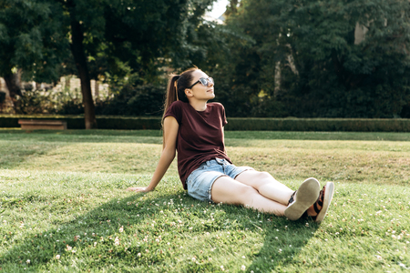 Beautiful young girl resting on the grass in a city park.の写真素材