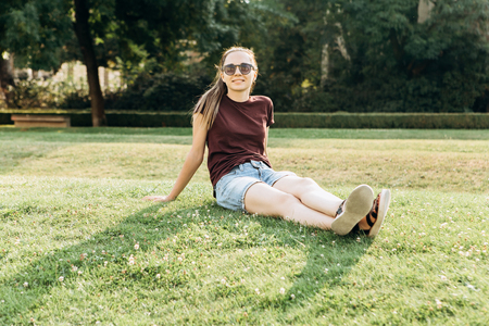 Beautiful young girl resting on the grass in a city park.の写真素材