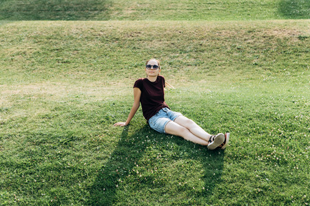 Beautiful young girl resting on the grass in a city park.の写真素材