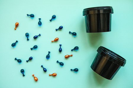 Many pills or capsules with hyaluronic acid and q10 or coenzyme next to a can or container with a face cream. Caring for skin health.の写真素材