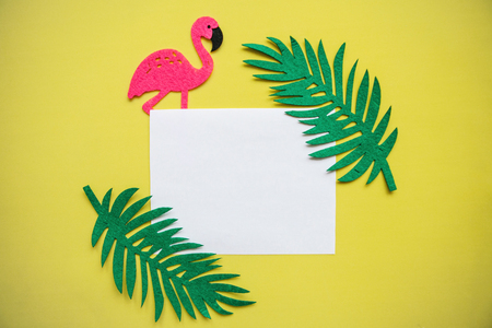 Summer design. Flamingo with tropical leaves on a yellow background. In the middle is a space for text.の写真素材