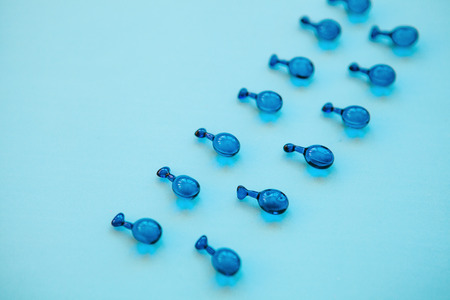 Fillers or capsules with hyaluronic acid on a blue background. Skin care and facial health.の写真素材