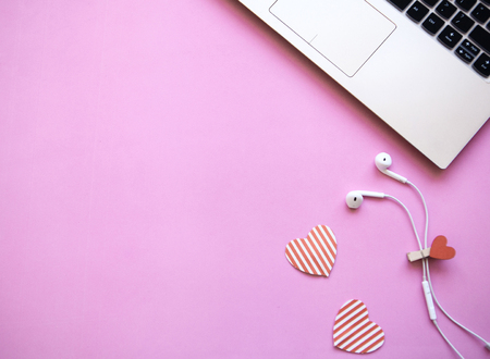 Workspace in pink trendy color. Laptop and headphones close by. Beginning of the holiday or the onset of Valentines Day or another love event. Near there is a place for text.の写真素材